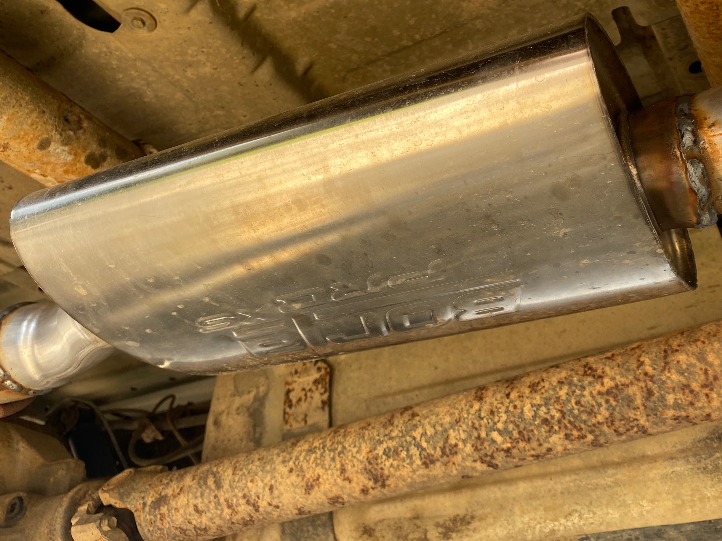 Borla performance muffler installed on a pickup truck's exhaust system, featuring a stainless steel welded design engineered to improve exhaust flow, horsepower, and exhaust tone.
