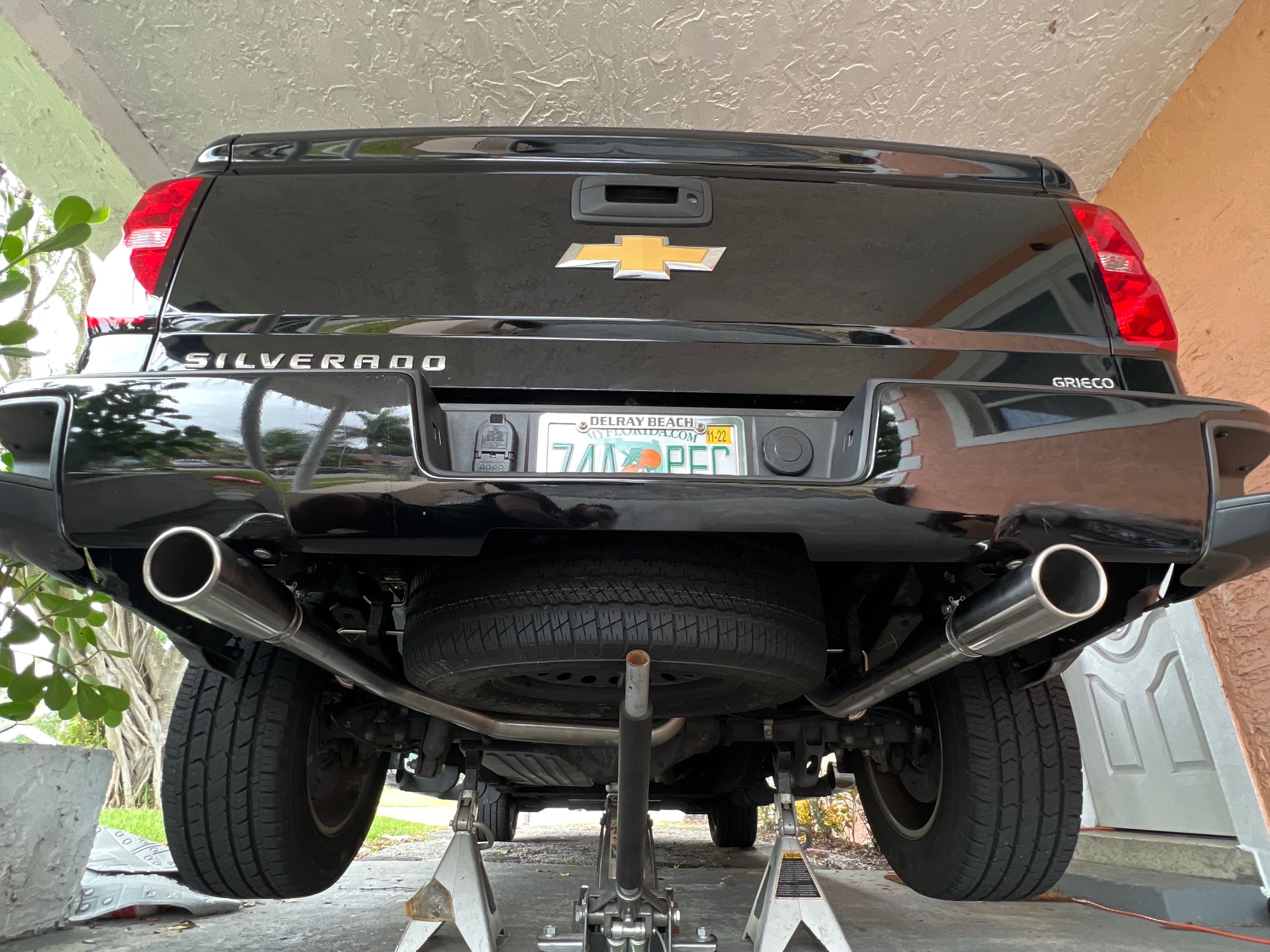 Rear view of a Chevrolet Silverado with a dual-exit cat-back exhaust system, featuring large polished exhaust tips extending behind the rear bumper for improved exhaust flow and a performance exhaust note.