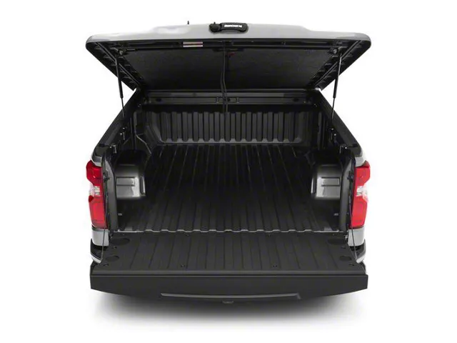 Pickup truck with a one-piece hinged tonneau cover raised open, revealing the full truck bed and gas struts that support easy cargo access.