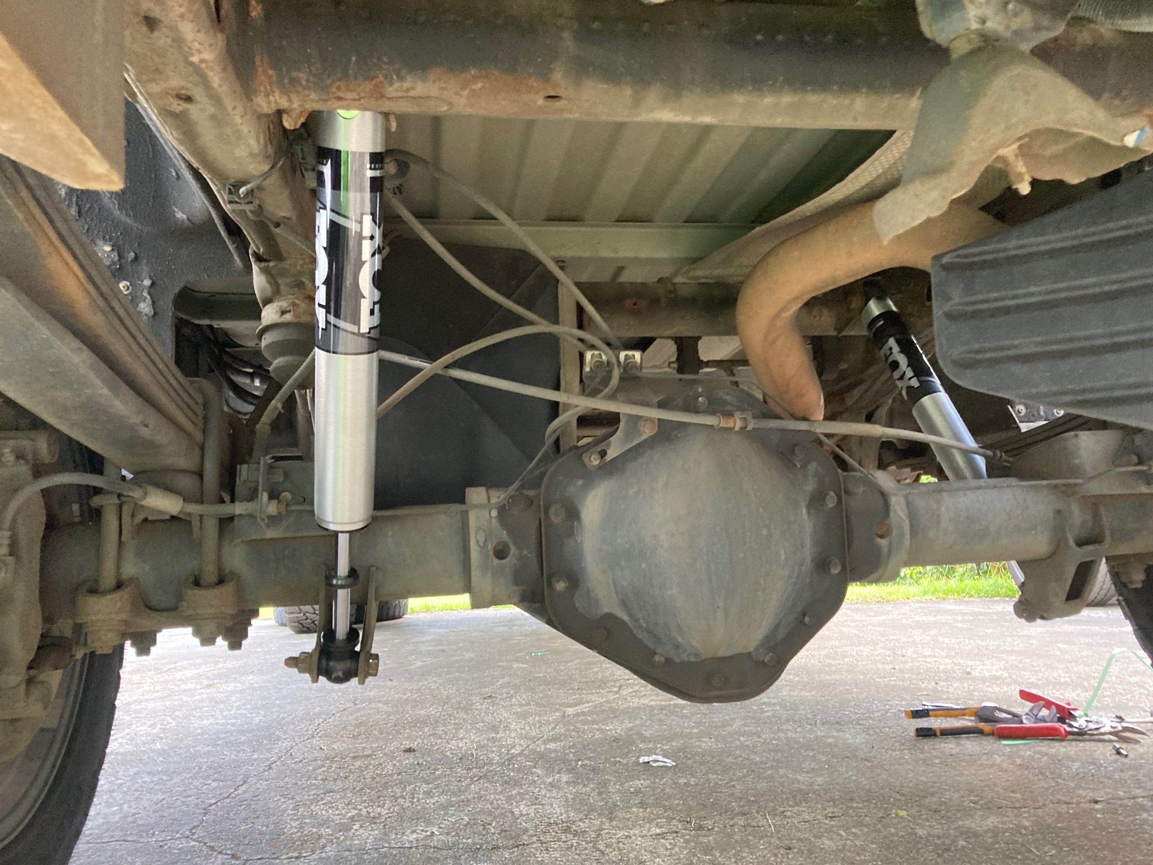 Fox Performance Series rear shock absorbers installed on a pickup truck's rear suspension, mounted between the frame and solid rear axle to improve off-road handling, ride control, and suspension performance.
