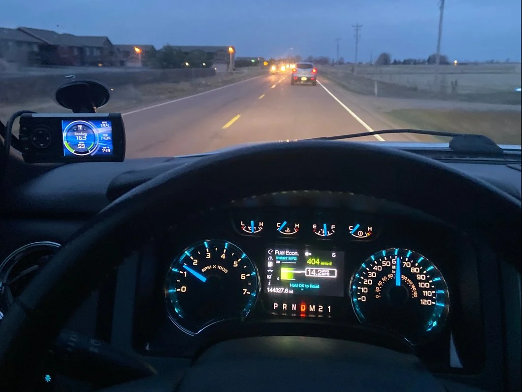 Edge Evolution CTS3 performance tuner mounted on a pickup truck windshield, displaying real-time engine gauges and vehicle performance data while driving.